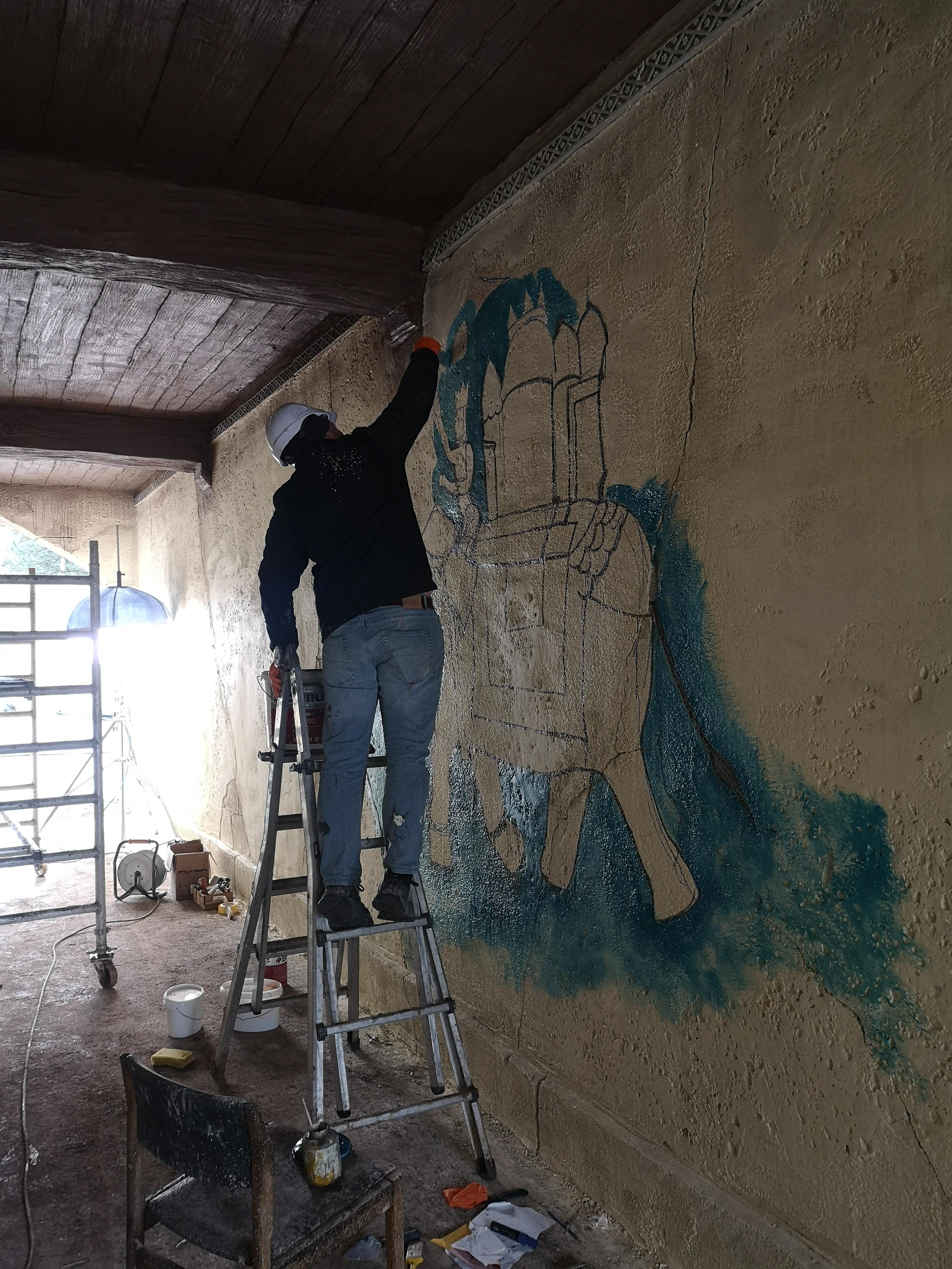 Ein Handwerker malt einen Elefanten auf eine Wand